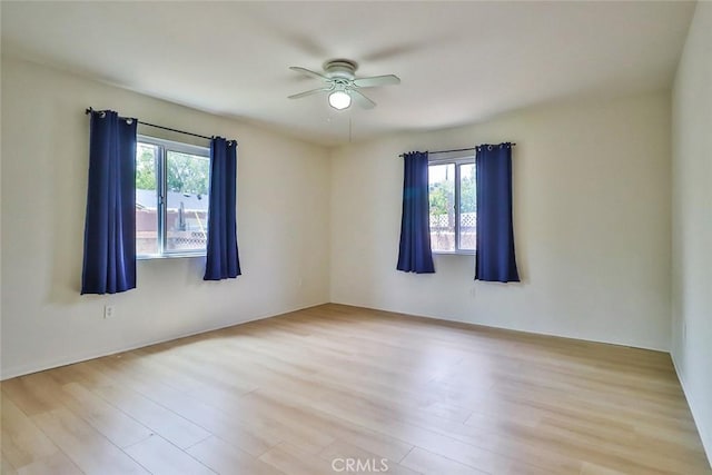 unfurnished room with plenty of natural light, ceiling fan, and wood finished floors