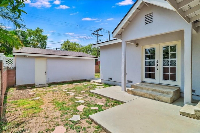 view of yard featuring fence, french doors, and an outbuilding