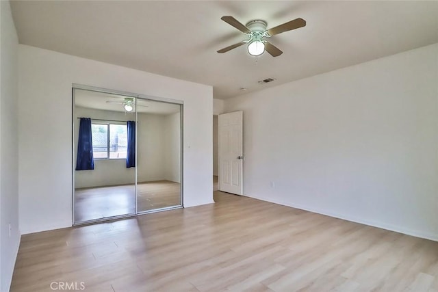 unfurnished bedroom featuring a ceiling fan, visible vents, wood finished floors, and a closet