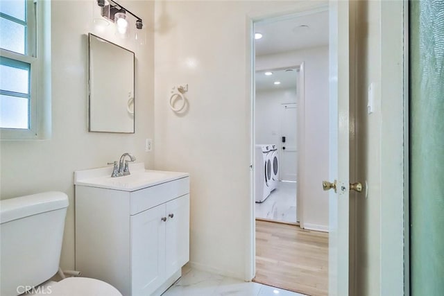 half bath featuring vanity, toilet, recessed lighting, baseboards, and washer and clothes dryer