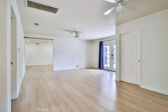 empty room with a ceiling fan, visible vents, and light wood finished floors