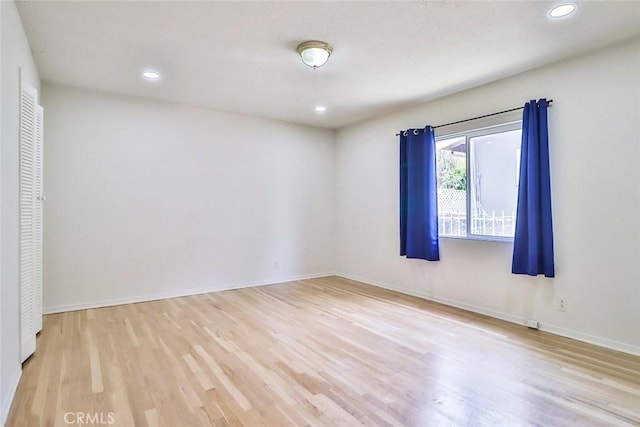 empty room featuring recessed lighting, baseboards, and light wood finished floors