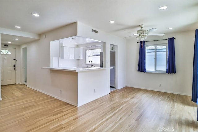 kitchen with light wood-type flooring, baseboards, ceiling fan, and visible vents
