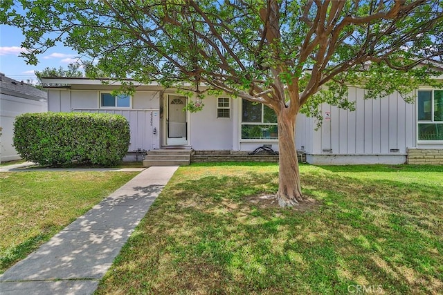 single story home featuring board and batten siding and a front yard