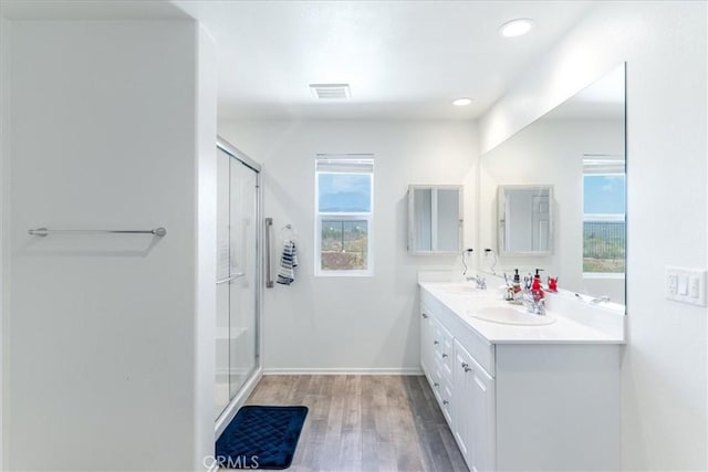 full bathroom featuring a sink, baseboards, wood finished floors, visible vents, and a stall shower