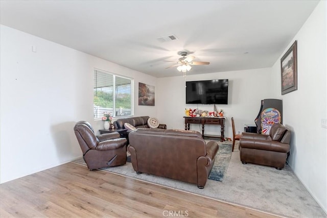 living area with ceiling fan, visible vents, and wood finished floors