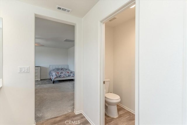 bathroom with toilet, wood finished floors, and visible vents