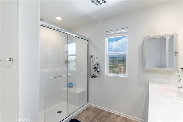 bathroom with visible vents, vanity, wood finished floors, baseboards, and a shower stall