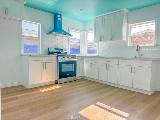4709 Bresee Ave, Baldwin Park, CA 91706 - kitchen featuring stainless steel range with gas stovetop, decorative backsplash, range hood, and light wood-type flooring
