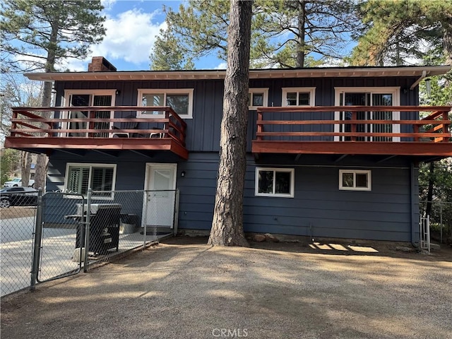 31347 Oakleaf Dr, Running Springs, CA 92382 - view of front of home with fence, a balcony, a chimney, a gate, and board and batten siding