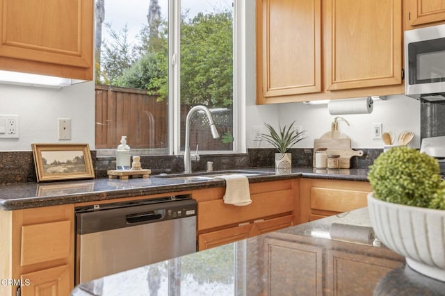 kitchen with dark stone counters, appliances with stainless steel finishes, and a sink