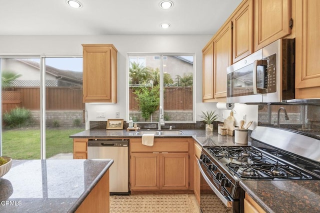 kitchen featuring dark stone countertops, recessed lighting, appliances with stainless steel finishes, and a sink