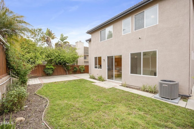 rear view of property with a patio, stucco siding, central AC unit, a fenced backyard, and a yard