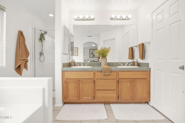 bathroom featuring double vanity, tile patterned floors, a shower stall, and a sink