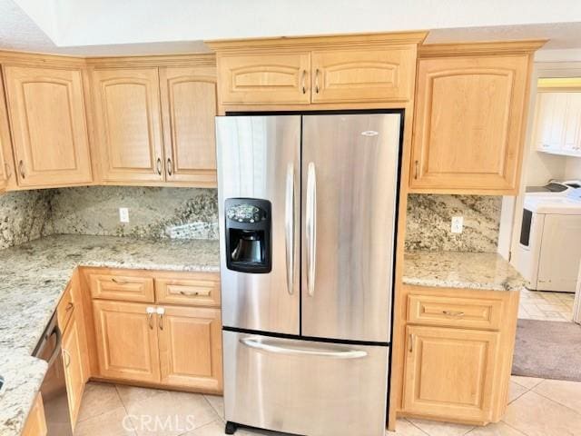 kitchen with light tile patterned floors, light brown cabinets, stainless steel refrigerator with ice dispenser, and washer and clothes dryer