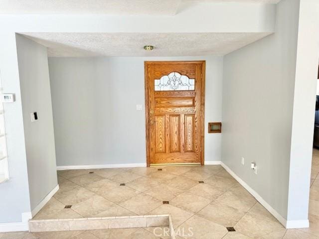 foyer featuring a textured ceiling, baseboards, and light tile patterned flooring