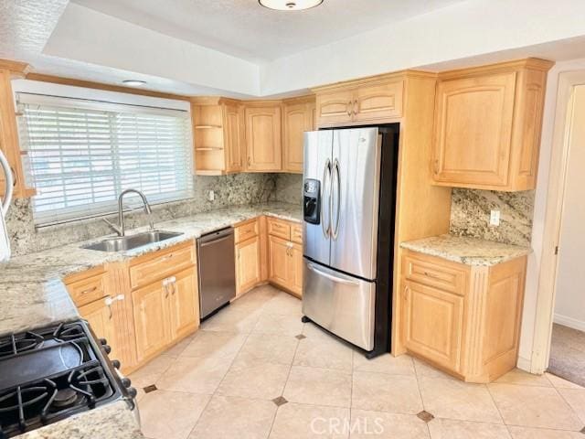 kitchen featuring a sink, stainless steel appliances, tasteful backsplash, a tray ceiling, and light brown cabinets