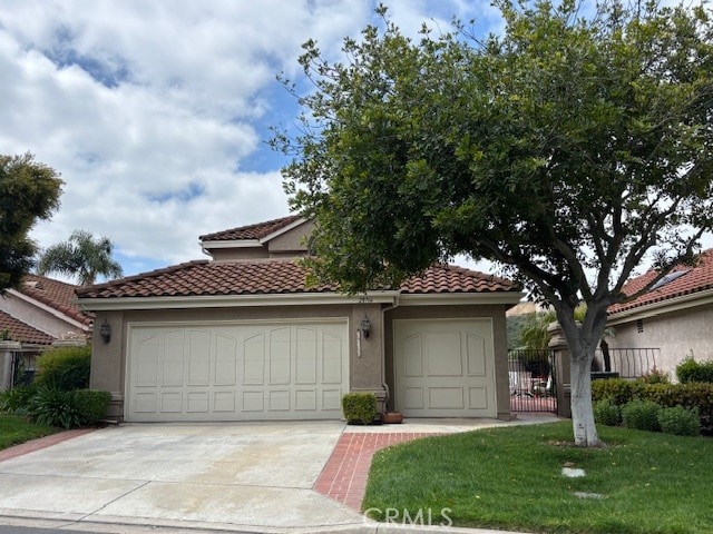 mediterranean / spanish house featuring a tiled roof, an attached garage, concrete driveway, and stucco siding