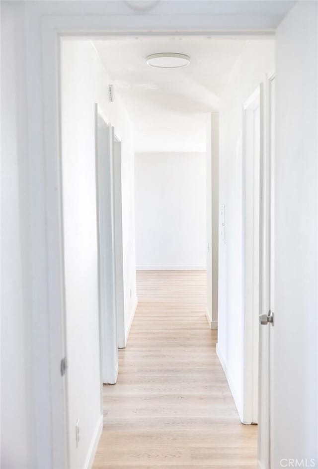 hallway featuring baseboards and light wood finished floors