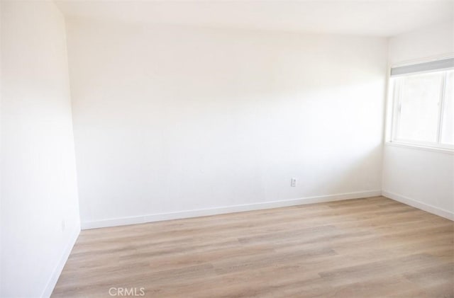 empty room featuring baseboards and light wood finished floors