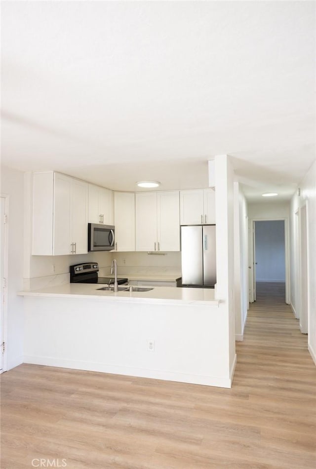 kitchen featuring light wood-type flooring, light countertops, white cabinets, and stainless steel appliances