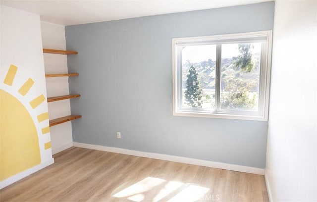 unfurnished room with baseboards and light wood finished floors