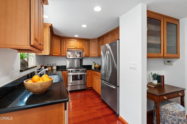 kitchen featuring appliances with stainless steel finishes, brown cabinets, a sink, recessed lighting, and dark wood-type flooring