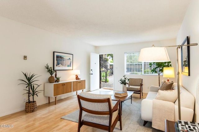 living area featuring baseboards and light wood-style flooring