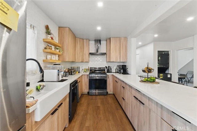 kitchen featuring light brown cabinetry, wall chimney range hood, light countertops, stainless steel appliances, and modern cabinets