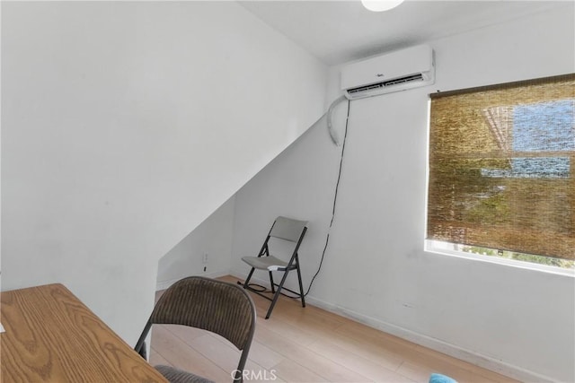 home office with an AC wall unit, baseboards, and light wood finished floors