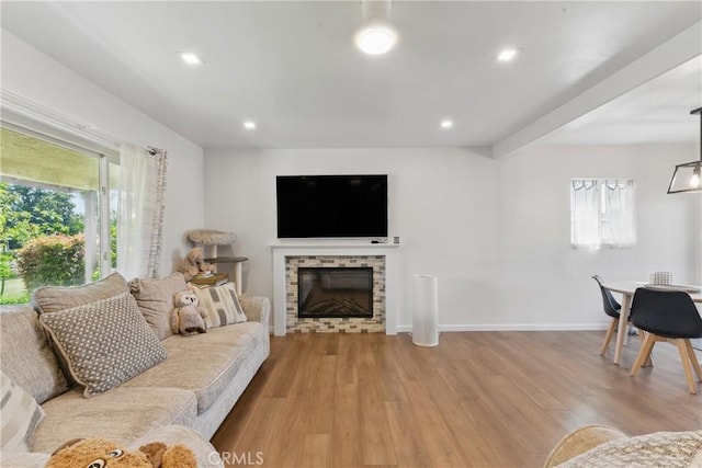 living room featuring baseboards, a fireplace, recessed lighting, and wood finished floors