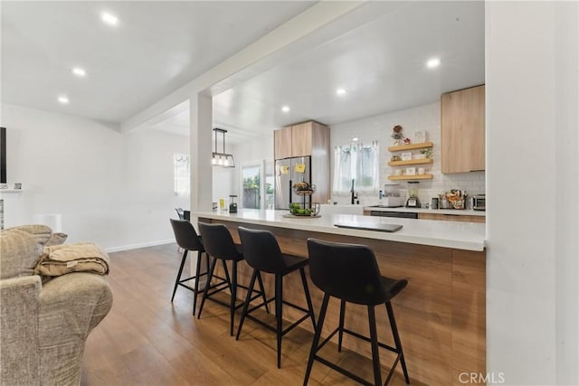 kitchen with stainless steel fridge, light countertops, a kitchen breakfast bar, open floor plan, and modern cabinets