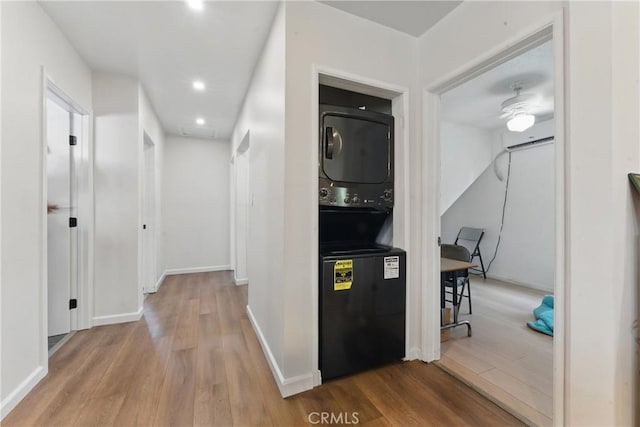 corridor with baseboards, stacked washer / drying machine, recessed lighting, and wood finished floors