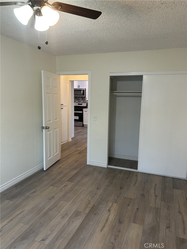 unfurnished bedroom with wood finished floors, a textured ceiling, a closet, and a ceiling fan