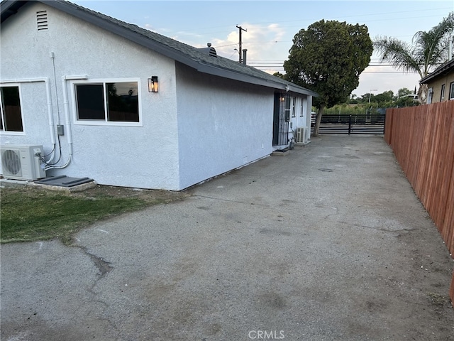 view of side of property with fence, stucco siding, and a cooling unit