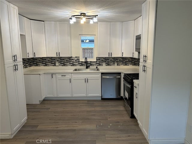 kitchen with a sink, gas stove, dishwasher, tasteful backsplash, and white cabinetry