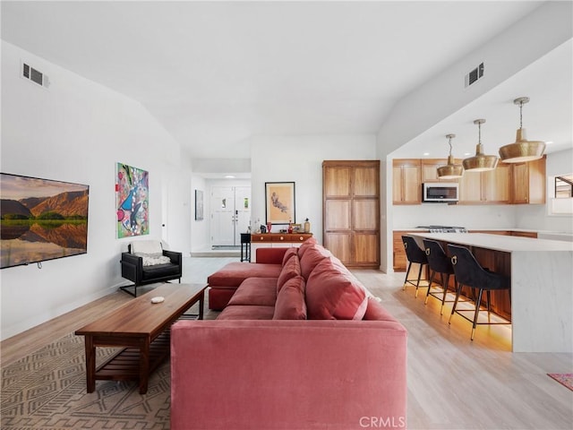 living room featuring baseboards, visible vents, and light wood-style flooring