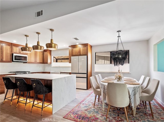 kitchen featuring freestanding refrigerator, a center island, light countertops, a sink, and light wood-style flooring