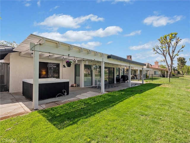 back of property featuring fence, a hot tub, stucco siding, a lawn, and a patio