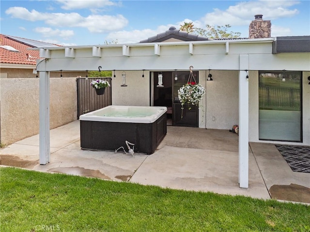 view of patio with a hot tub and fence