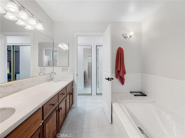 full bathroom featuring double vanity, a sink, tile patterned flooring, and tiled tub