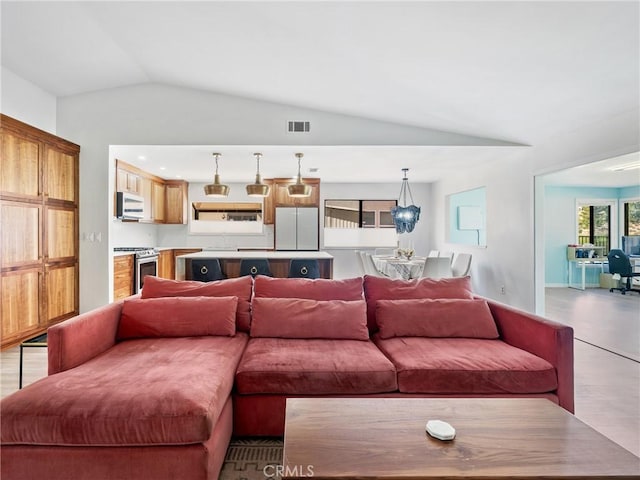 living area with visible vents, light wood finished floors, and vaulted ceiling