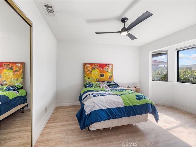 bedroom featuring baseboards, visible vents, ceiling fan, and light wood-style floors