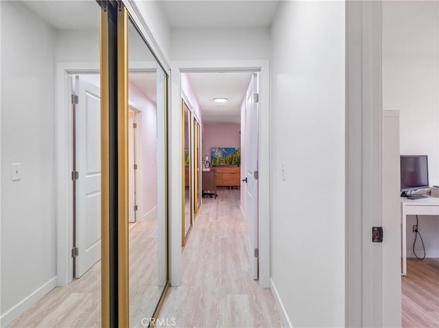 hall featuring baseboards and light wood finished floors