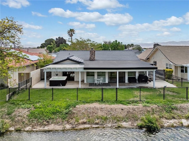 back of house featuring a lawn, a fenced backyard, a patio area, and a water view