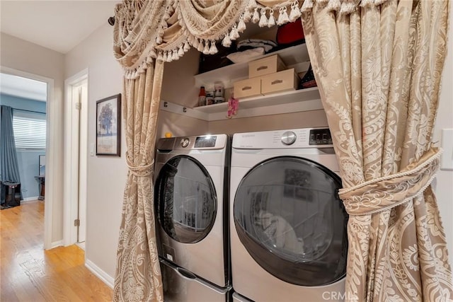 washroom with washer and dryer, laundry area, baseboards, and wood finished floors