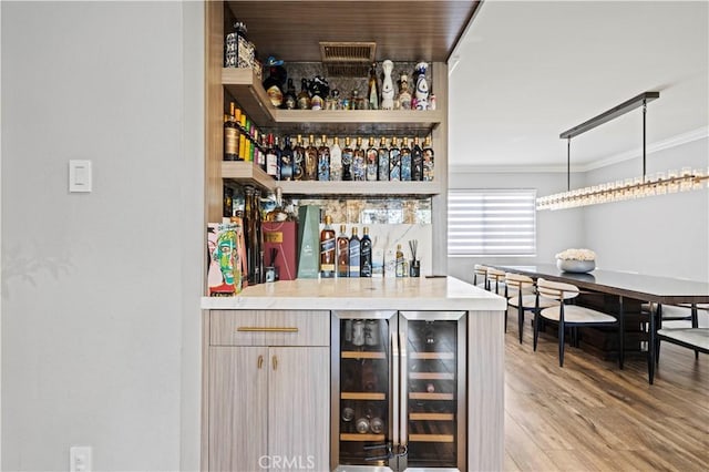 bar featuring visible vents, a dry bar, light wood finished floors, wine cooler, and ornamental molding