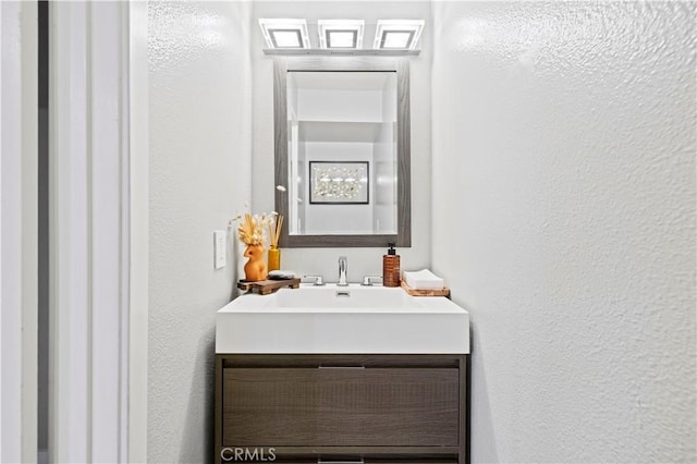 bathroom featuring a textured wall and vanity