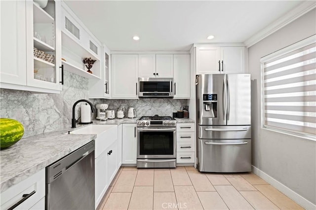 kitchen featuring white cabinets, light tile patterned flooring, a sink, stainless steel appliances, and backsplash
