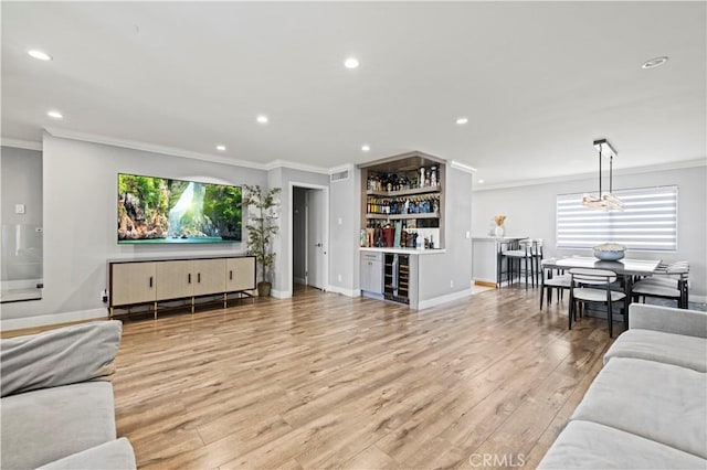 living area with ornamental molding, a bar, recessed lighting, and beverage cooler